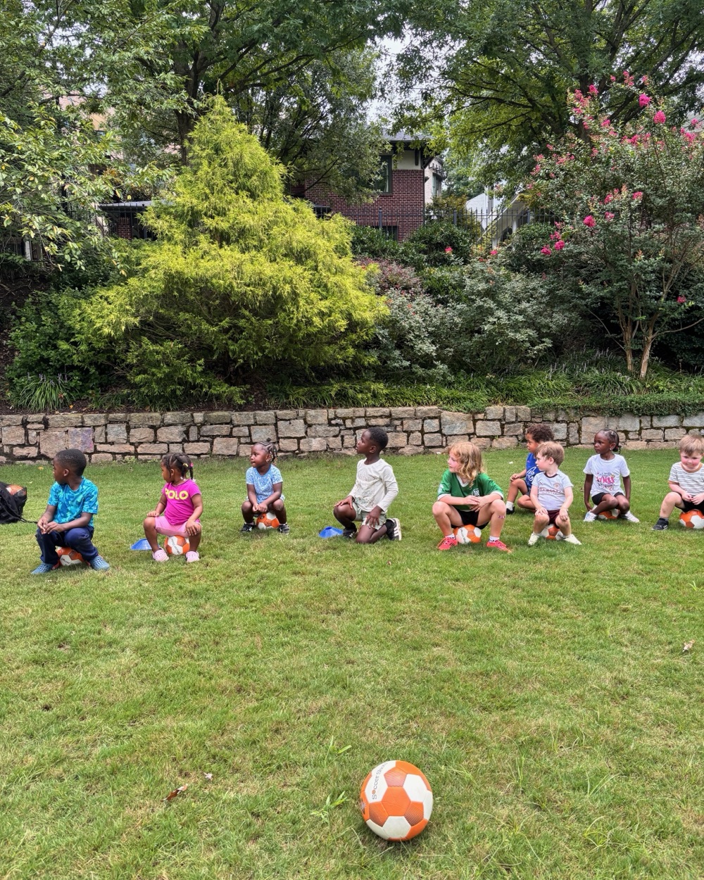 Children seated on the field with a soccer ball