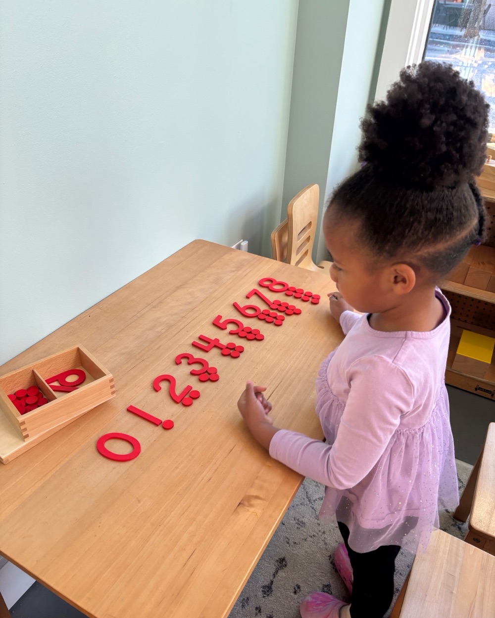 A child arranging sandpaper numerals at a table